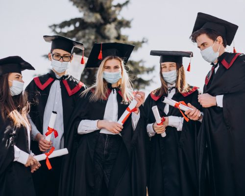 group-of-students-celebrating-graduation-together-and-wearing-face-masks